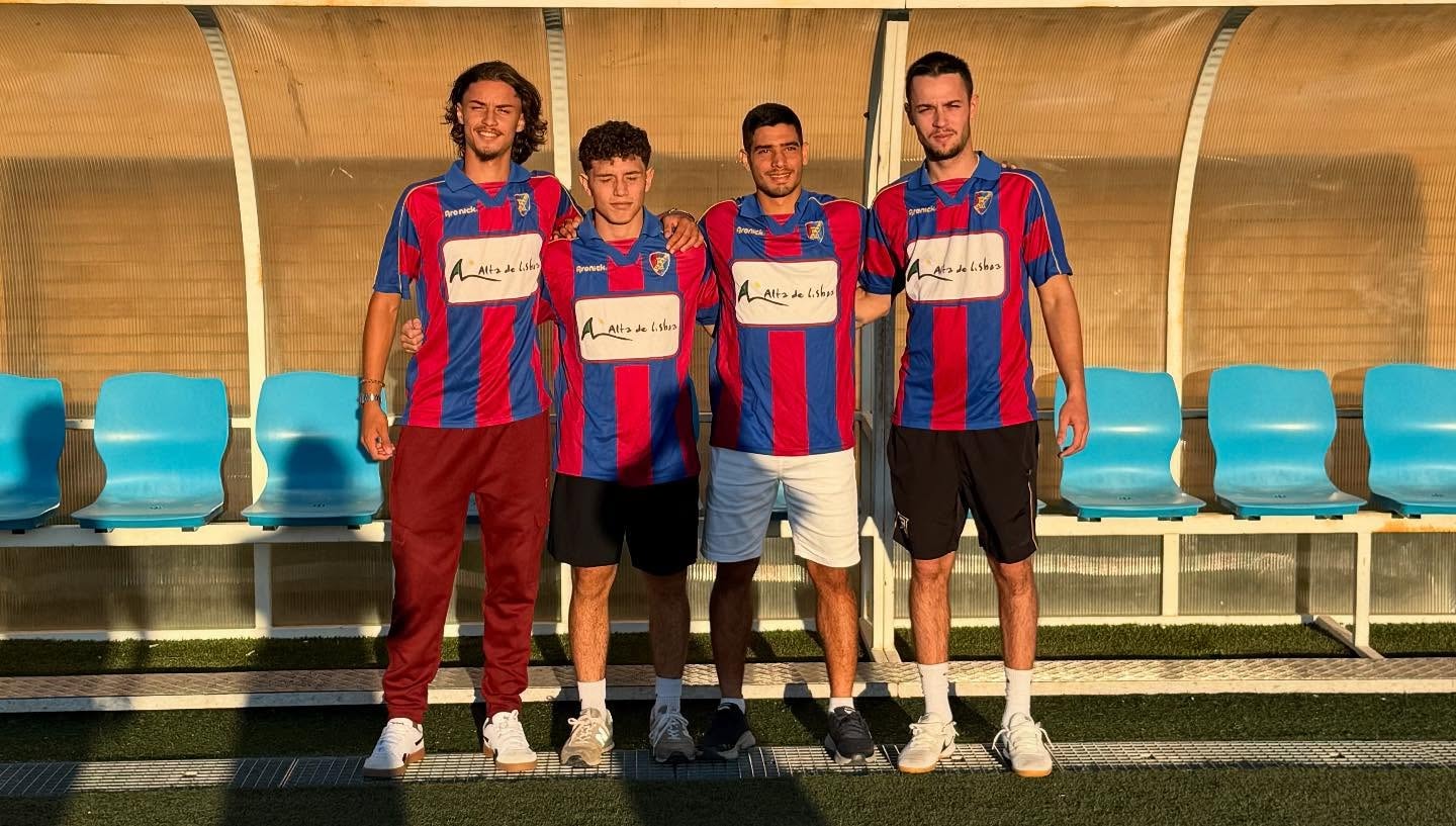 Four soccer players posing at the stadium